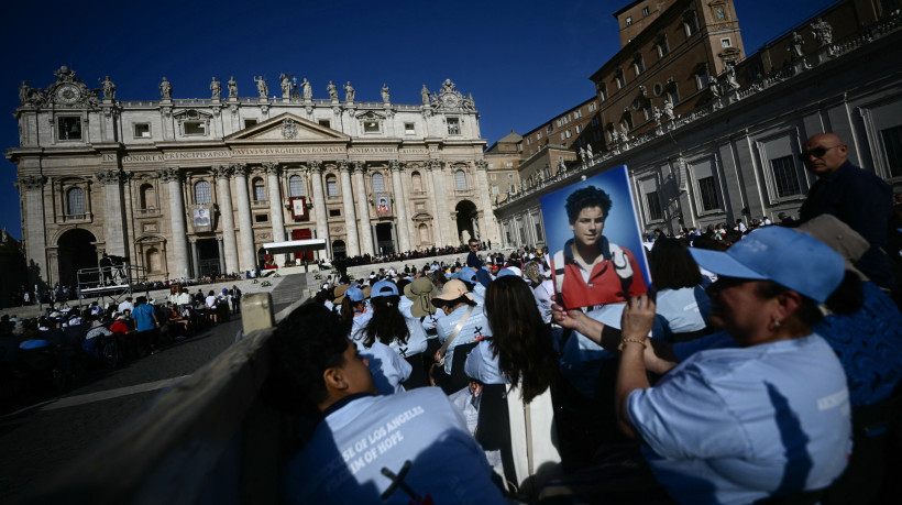 Um fiel segura um retrato de Carlo Acutis em frente à Basílica de São Pedro, antes da Santa Missa e da cerimônia de canonização no Vaticano, em 7 de setembro de 2025.
