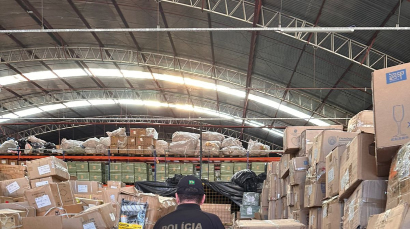 Agente da PF vistoria um dos galpões com mercadorias importadas sob esquema de fraude fiscal, alvo da operação Snooker