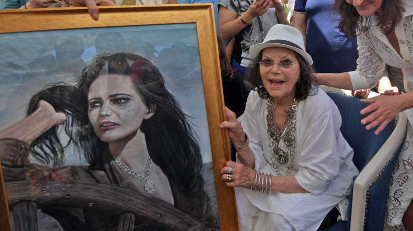 Claudia Cardinale posa ao lado de um quadro com sua imagem durante a abertura de uma rua com o seu nome em La Goulette, na Tunísia, em 2022