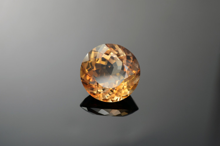 Imagem de apoio ilustrativo de um diamante castanho lapidado. O diamante castanho reflete feixes de luz verdes e vermelhos, trazendo um aspecto castanho ao mineral