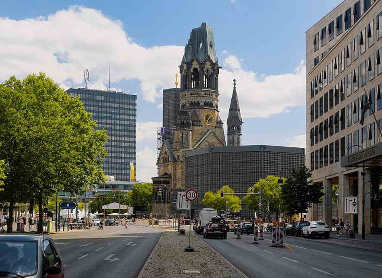 Igreja Kaiser Wilhelm (Kaiser-Wilhelm-Gedächtniskirche) - Descrição: Esta igreja foi bombardeada durante a Segunda Guerra Mundial e suas ruínas foram mantidas como um memorial. Ao lado, há uma moderna torre construída nos anos 1960 - Localização: Breitscheidplatz - Referências Históricas: O contraste entre as ruínas e a nova torre simboliza a destruição e a reconstrução de Berlim