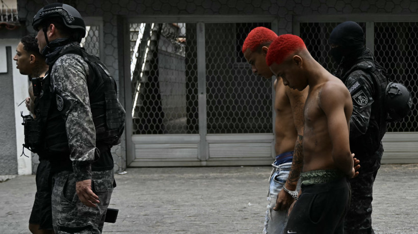 Policiais escoltam suspeitos presos durante a Operação Contenção para fora da favela Vila Cruzeiro, no Complexo da Penha, no Rio de Janeiro, Brasil, em 28 de outubro de 2025.