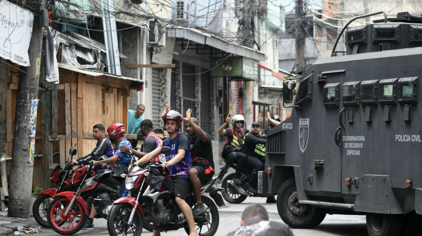 Motociclistas e passageiros levantam as mãos em sinal de não ameaça enquanto policiais entram na favela de Vila Cruzeiro, no Complexo da Penha, no Rio de Janeiro, Brasil, em 28 de outubro de 2025 