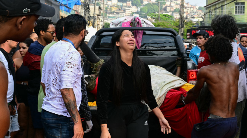 Uma mulher chora enquanto pessoas descarregam corpos de uma caminhonete na Praça São Lucas, na favela de Vila Cruzeiro, no complexo da Penha, no Rio de Janeiro, após a Operação Contenção.
