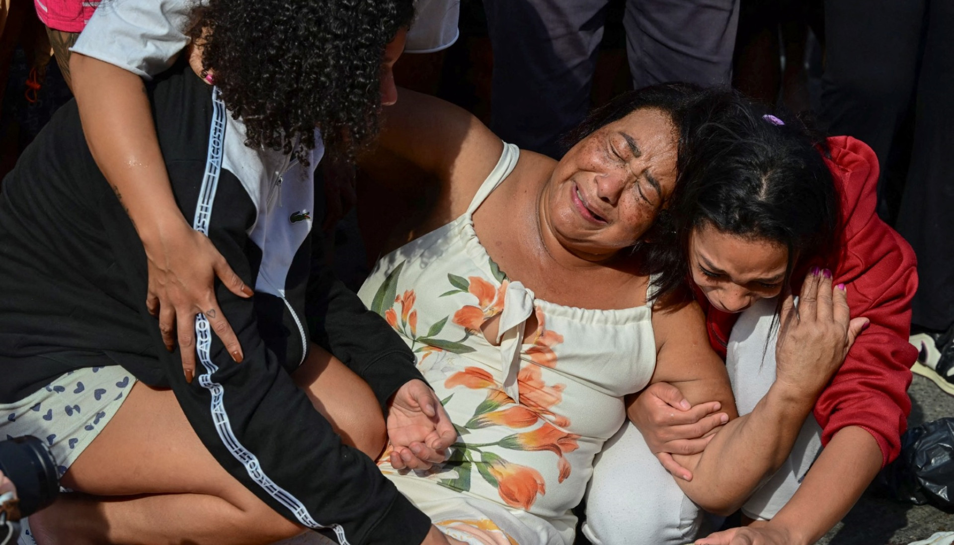 ￼MULHERES choram junto do corpo de homem morto, na praça São Lucas, na favela Vila Cruzeiro, no Complexo da Penha, no Rio de Janeiro (Foto: PABLO PORCIUNCULA / AFP)