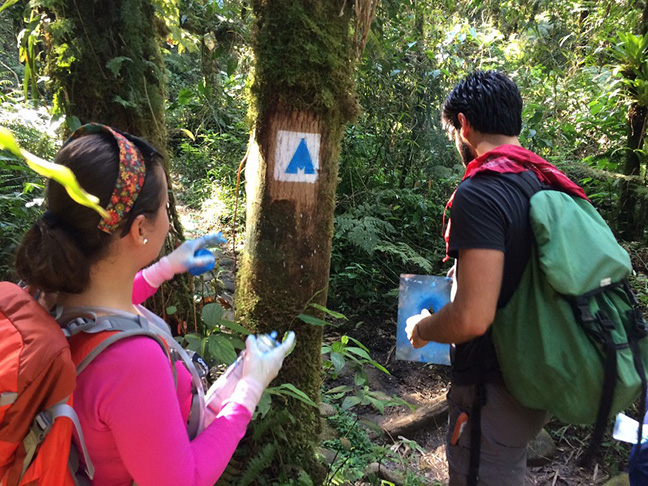 Eles usam estêncil para aplicar uma pintura rústica. E fica mais fácil carregar o material para a sinalização sem prejudicar a natureza. 