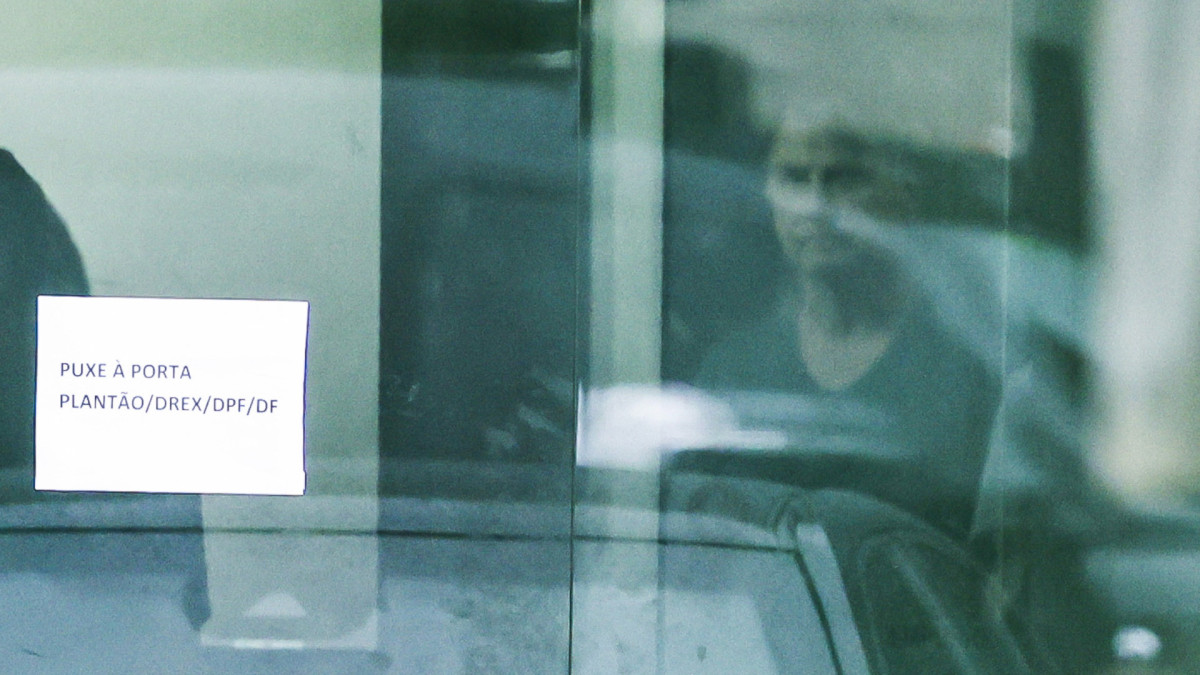 Bolsonaro através da porta da sede da Polícia Federal, onde está preso, ao final da visita da ex-primeira-dama Michelle Bolsonaro 