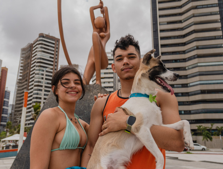 FORTALEZA, CEARÁ, BRASIL, 23-11-2025: Reportagem sobre as condições estruturais de estátuas e esculturas da orla da Beira Mar e Praia de Iracema. Na foto, Gabriel Rauan, 24, natural de Sobral, e ao fundo a estátua "Iracema Guardiã", do artista Zenon da Cunha Mendes Barreto, de 1995, na Praia de Iracema. (Foto: Fernanda Barros/ O Povo)