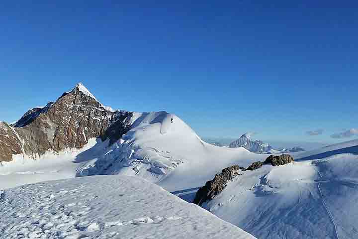 Lyskamm (4.527 m) - Situado no maciço do Monte Rosa, é conhecido tanto pela sua imponência quanto pela reputação desafiadora que ganhou entre montanhistas. Apesar disso, sua silhueta sinuosa e a vista contínua sobre vastas geleiras fazem dele um dos picos mais marcantes dos Alpes Peninos, combinando beleza e respeito em igual medida.
