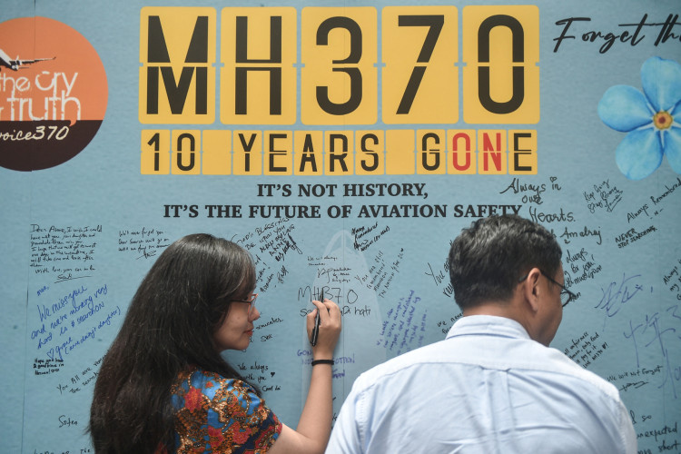 Uma mulher escreve uma mensagem durante um evento realizado por familiares dos passageiros desaparecidos e apoiadores para marcar o 10º aniversário do desaparecimento do voo MH370 da Malaysia Airlines. As buscas serão retomadas no final de dezembro.