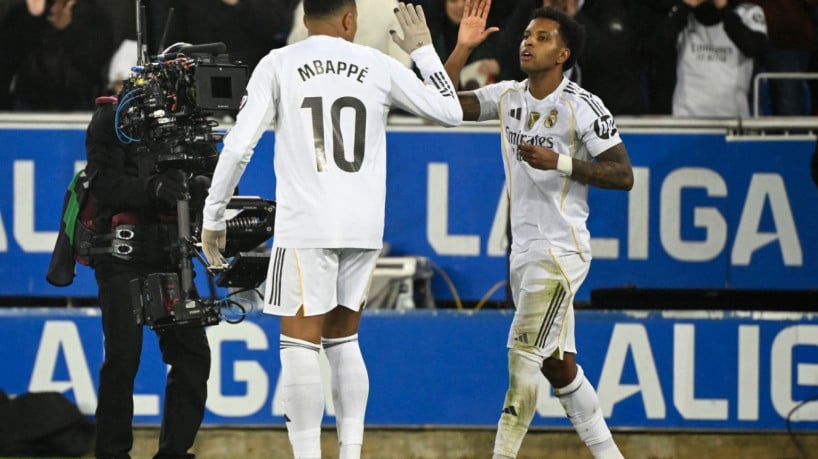 Real Madrid's Brazilian forward #11 Rodrygo celebrates scoring his team's second goal with Real Madrid's French forward #10 Kylian Mbappe during the Spanish league football match between Deportivo Alaves and Real Madrid CF at the Mendizorroza stadium in Vitoria on December 14, 2025. 