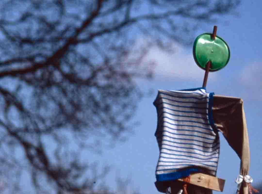 Espantalho de pouca elaboração, com rosto redondo em verde e sem traços. 

