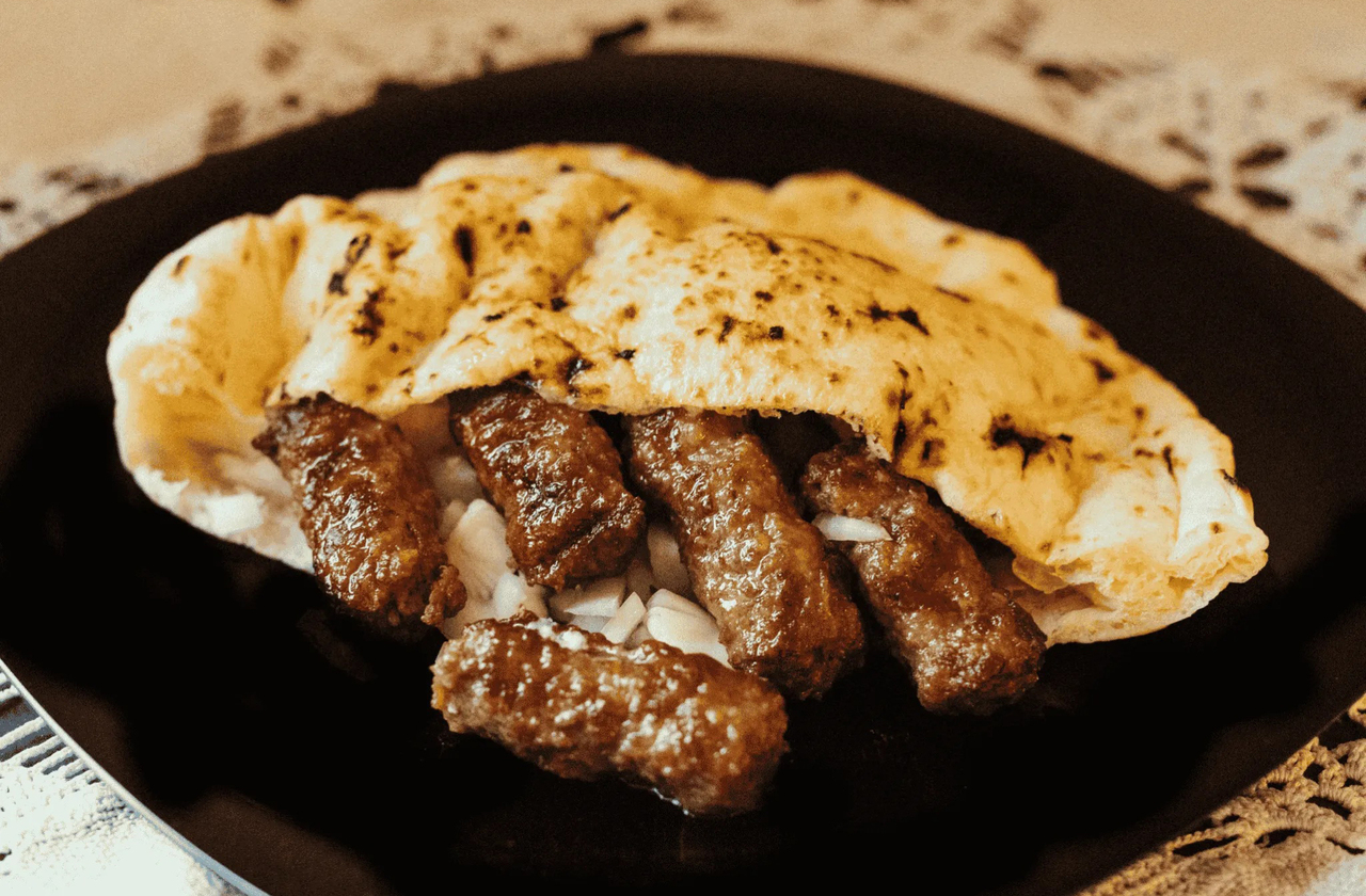 A gastronomia local combina influências turcas, balcânicas e mediterrâneas, com pratos como cevapi, burek e baklava. Cafés servem o tradicional café bósnio preparado em cezve de cobre, enquanto restaurantes à beira do Neretva oferecem vistas inesquecíveis da ponte.