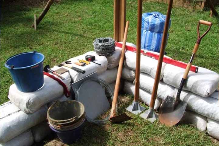 Os materiais necessários incluem sacos de polipropileno, arame farpado, terra úmida, brita e equipamentos de medição.