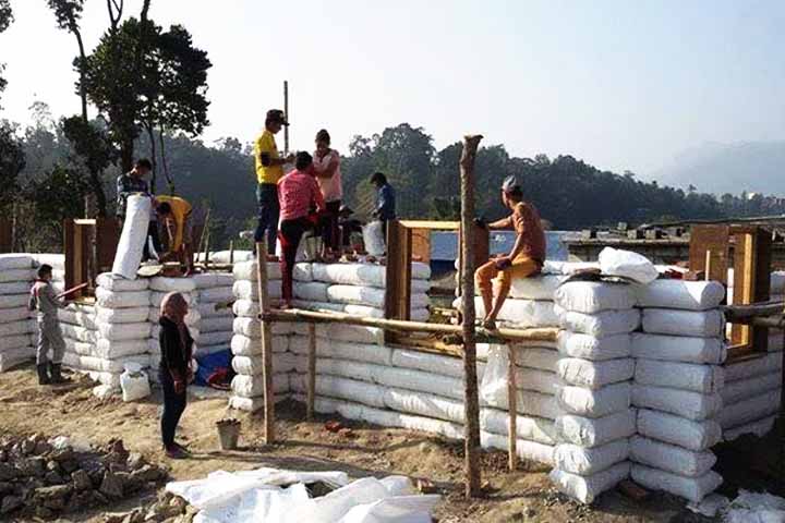 As paredes são erguidas a partir do empilhamento de camadas de sacos, compactados e alinhados com arame, até que a estrutura esteja completa.