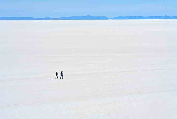 Durante a estação seca, o salar se transforma em uma vasta planície branca, onde o sal cobre a superfície em uma camada espessa, criando uma vista surreal de imensidão e simetria.