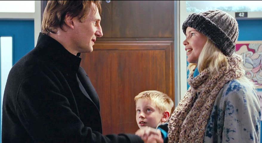 Nessa participação, o personagem Daniel, interpretado por Liam Neeson, conhece Carol, vivida por Schiffer, na escola de seu enteado Sam, papel de Thomas Brodie-Sangster, e tenta um primeiro flerte. 
