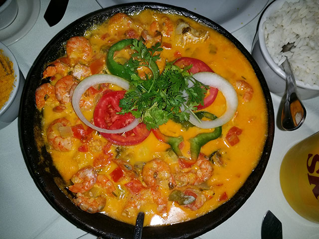 Moqueca baiana: Um prato de peixe cozido com azeite de dendÃª, leite de coco, cebola, tomate e pimentÃ£o, cheio de sabores marcantes. Geralmente servido com pirÃ£o e arroz. Calorias: cerca de 170 kcal.