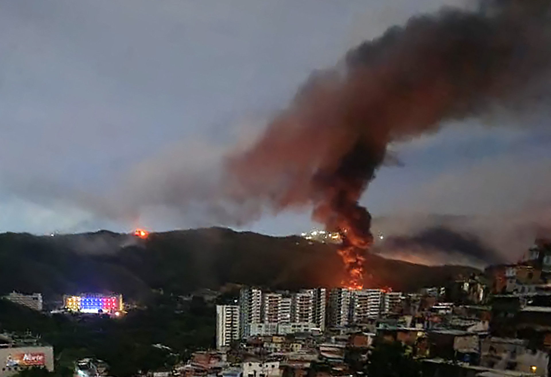 Incêndio em Fuerte Tiuna, o maior complexo militar da Venezuela, após uma série de explosões em Caracas em 3 de janeiro de 2026. Militares dos Estados Unidos estiveram por trás de uma série de ataques contra a capital venezuelana, Caracas (Foto: STR / AFP)