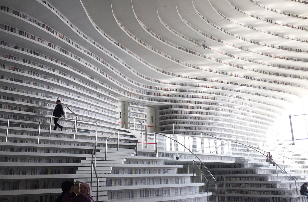 As estantes guardam milhares de volumes como ondas literárias, um oceano de páginas que se confunde com arte. O visitante mergulha nesse mar e se perde em narrativas, descobrindo que leitura também pode ser experiência visual.