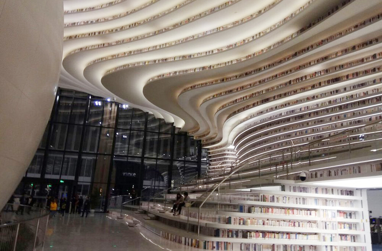 Suas estantes vão além das prateleiras comuns: têm ondas que se desdobram em movimento, como se fossem rochas de papel moldadas pela imaginação. O olhar percorre curvas infinitas que convidam à exploração, transformando cada livro em parte de uma escultura viva.

