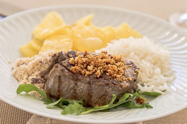 A receita surgiu a partir de suas preferências pessoais — filé alto com muito alho frito, acompanhado de arroz, farofa e batatas portuguesas — e fez tanto sucesso entre os clientes que acabou incorporada ao cardápio.