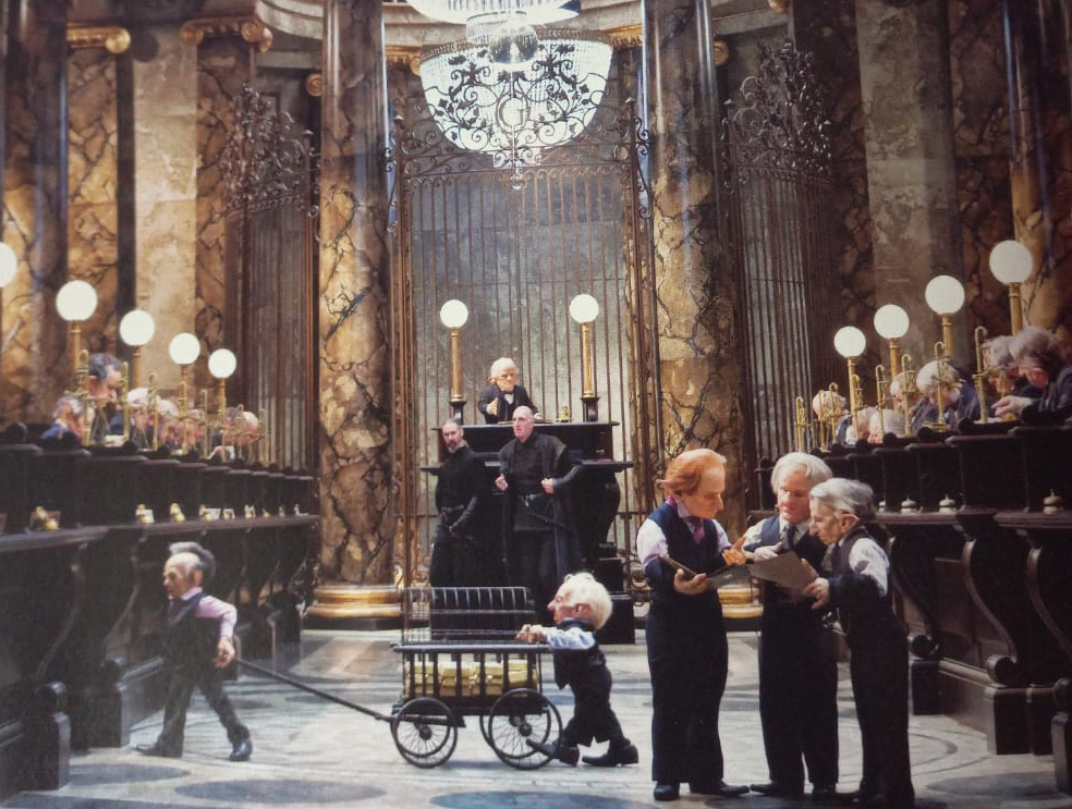 <p>A parte interna do banco é sofisticada, com grandes colunas de mármore. O cenário é harmonioso, com lustres, luminárias e bancadas para atendimento, feito por duendes.</p>
