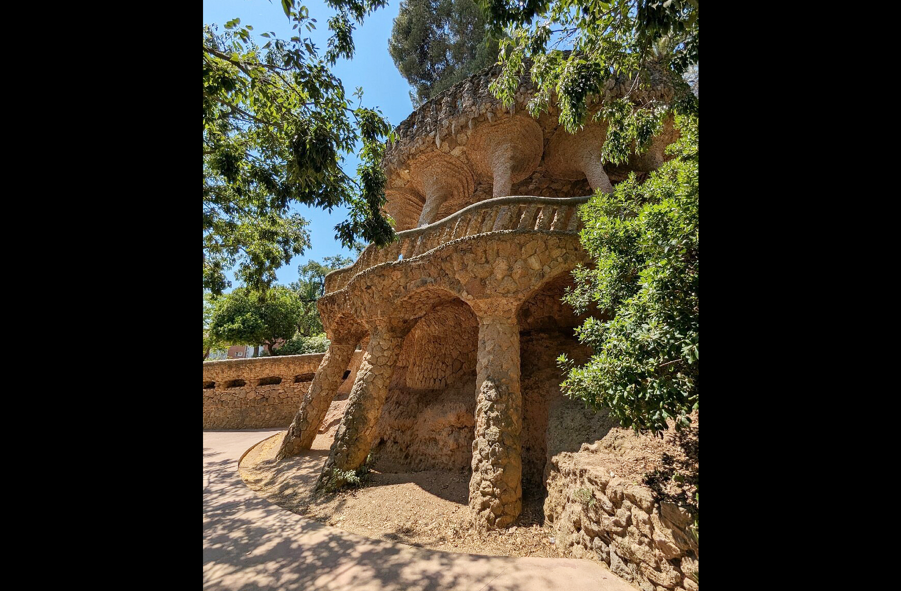 Os caminhos do parque são sustentados por viadutos de pedra que se confundem com a paisagem. As colunas inclinadas lembram troncos de árvores, criando um ambiente natural. Esses percursos foram pensados para facilitar o acesso sem agredir o terreno. É uma experiência de caminhar por uma obra de arte viva. A arquitetura se torna parte da caminhada.