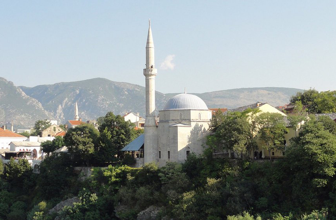 Construída no século 17, a mesquita oferece um dos melhores mirantes para fotografar a ponte. Seu interior preserva caligrafias otomanas e vitrais coloridos que filtram a luz. A subida ao minarete, por sinal, é uma experiência imperdível para quem visita Mostar.