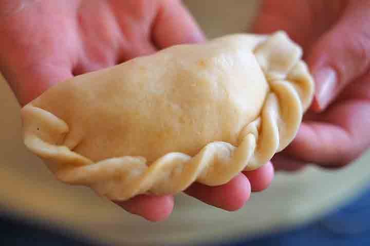<p>O preparo envolve abrir a massa, colocar o recheio no centro, dobrar e selar as bordas com os dedos ou um garfo. Dependendo da região, elas podem ser assadas em forno ou fritas em óleo quente.</p>
