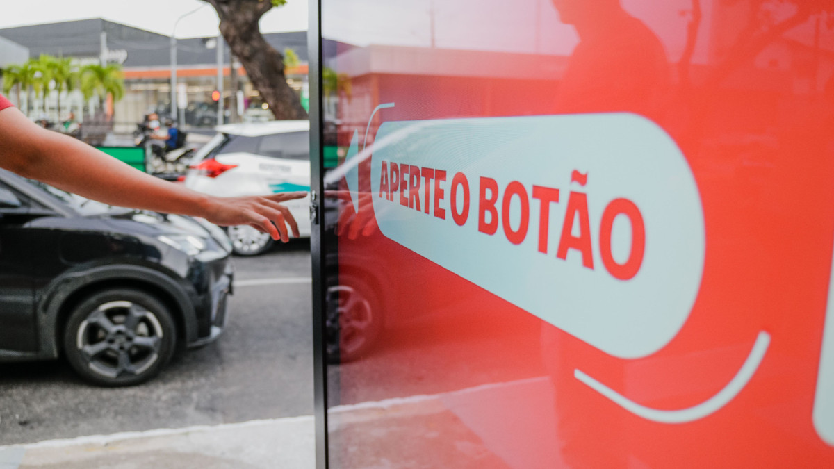 FORTALEZA, CEARÁ, BRASIL, 26-01-2026: Inauguração do Abrigo Amigo, pela Prefeitura de Fortaleza, em conjunto com Claro, Eletromídia, Etufor e UrbNews. A parada de ônibus conta com monitoramento e painel de led com acesso à central de apoio, com chamada de vídeo ao vivo. A solenidade ocorreu na Av. Humberto Monte, na parada próxima à UFC Campus do Pici. Na foto, uma pessoa testa a função de clicar no dispositivo. (Foto: Fernanda Barros/ O Povo)