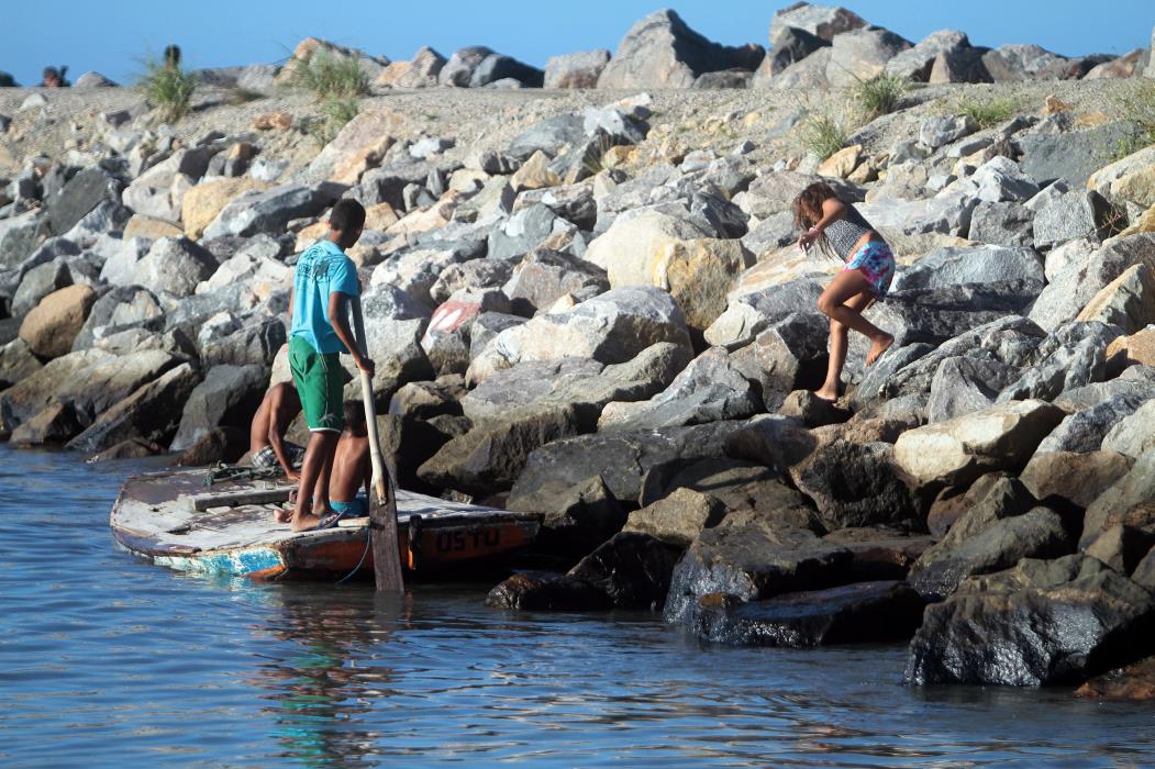 Crianças chegaram a brincar na água, perto da mancha de óleo fixada nas pedras   (Foto: Igor de Melo, em 05/07/2012)