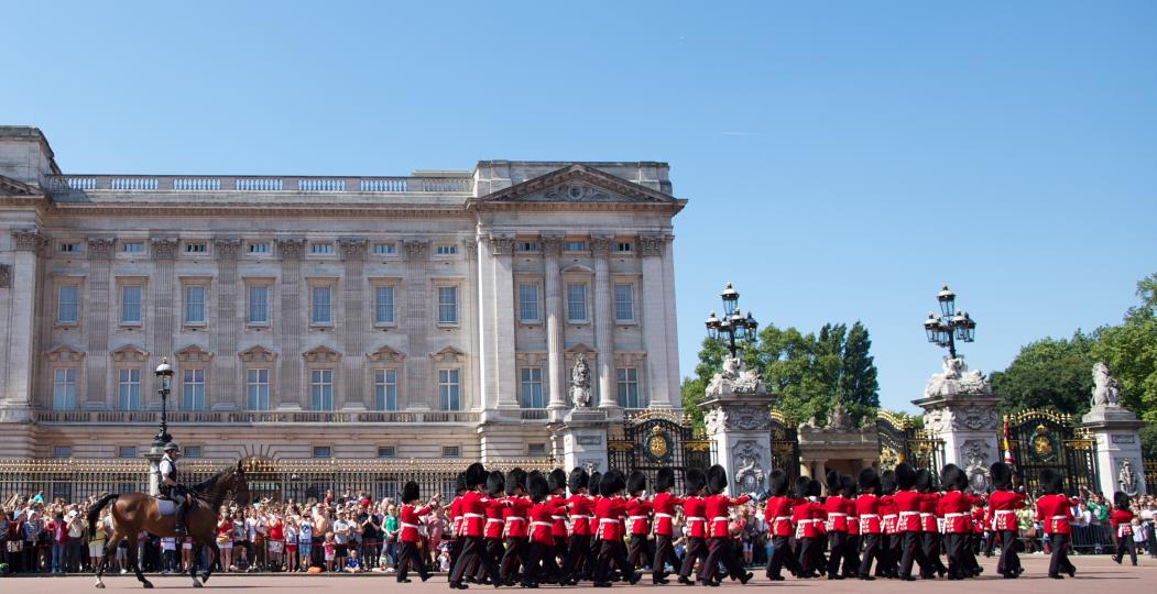 People watch from the pavement as Guardsmen followed by a mounted policeman march into Buckingham Palace during the Changing of the Guard in London on July 23, 2012, four days before the start of the London 2012 Olympic Games. AFP PHOTO / ANDREW COWIE