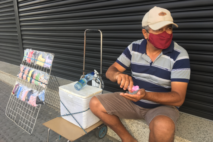 Ambulante Cícero Gomes passa álcool em gel nas mãos enquanto trabalha normalmente no centro de Juazeiro do Norte nesta sexta-feira, 9
