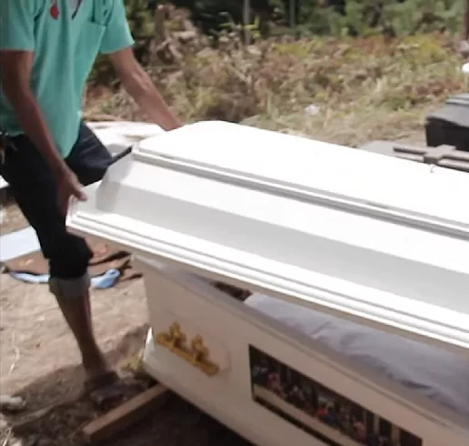 Enquanto crianças observam, os adultos cavam buracos onde os caixões de seus entes queridos estão enterrados, depois tiram os caixões e abrem as tampas.