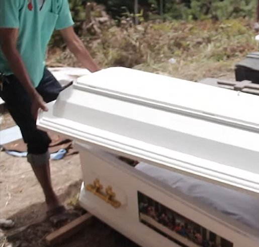 Enquanto crianças observam, os adultos cavam buracos onde os caixões de seus entes queridos estão enterrados, depois tiram os caixões e abrem as tampas.