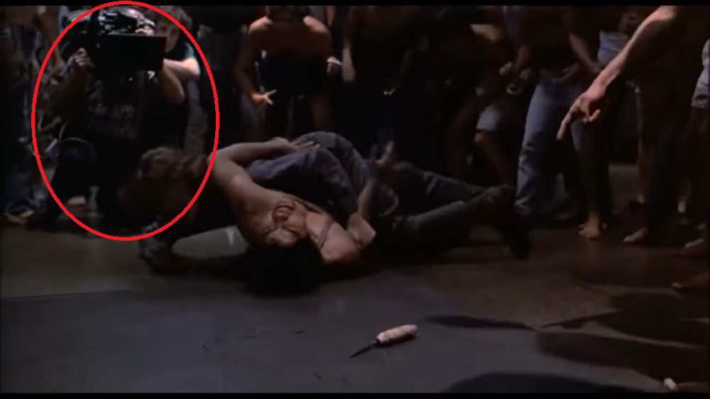 Câmera em “Juventude em Fúria” (1983): Nesse filme policial dos anos 80, em uma cena de briga na prisão, aparece simplesmente o operador de câmera ao fundo, enquanto a luta acontecia! 