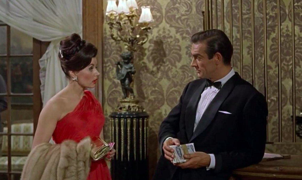 Coube à atriz Eunice Gayson a função de primeira Bond Girl da história. Ela também teve a sorte de ser a primeira agraciada com o clássico bordão “Bond… James Bond”, ao perguntar o nome do herói.
