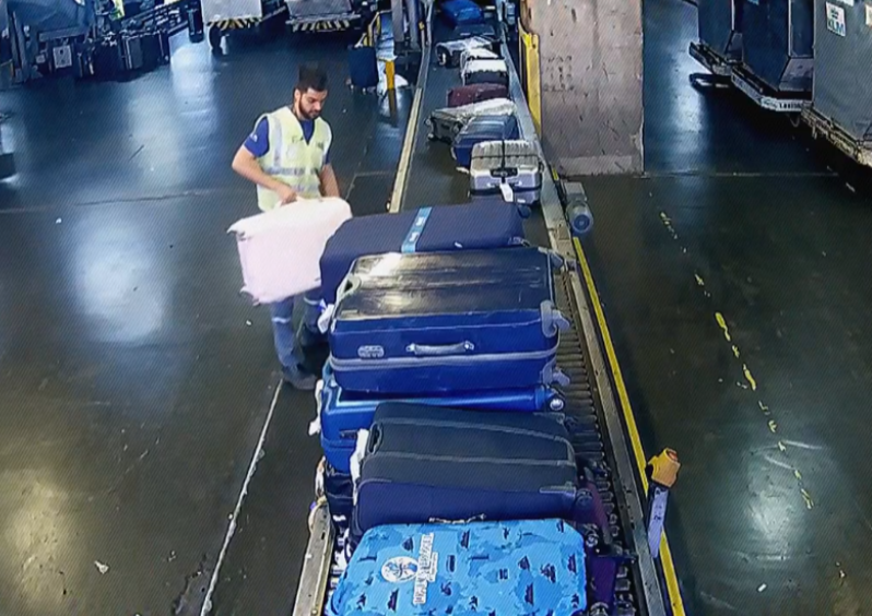 O funcionário Eduardo dos Santos pega a mala rosa de Jeanne e a coloca no chão. 