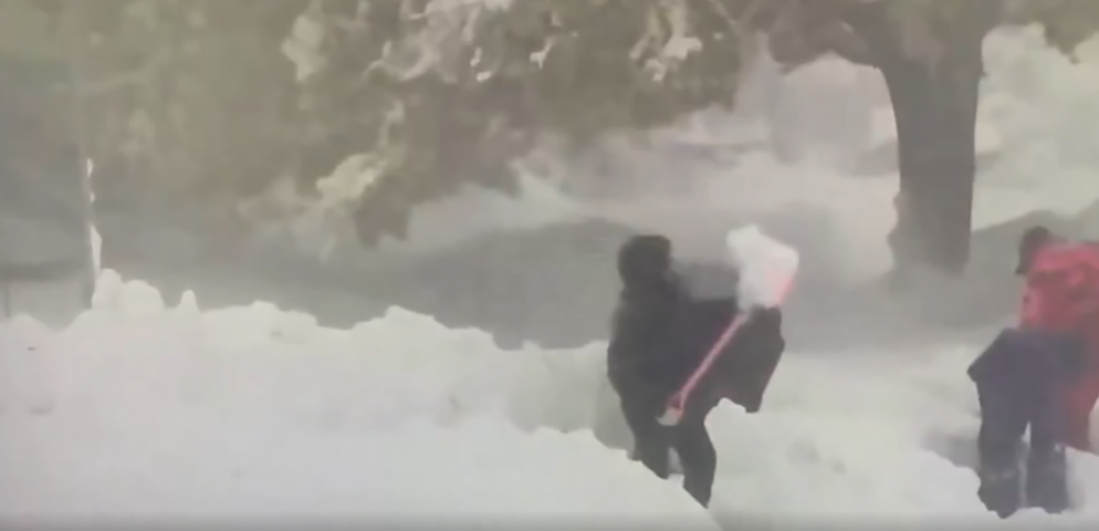 Muita gente ajudava a tentar retirar neve em torno de veículos nas ruas.  