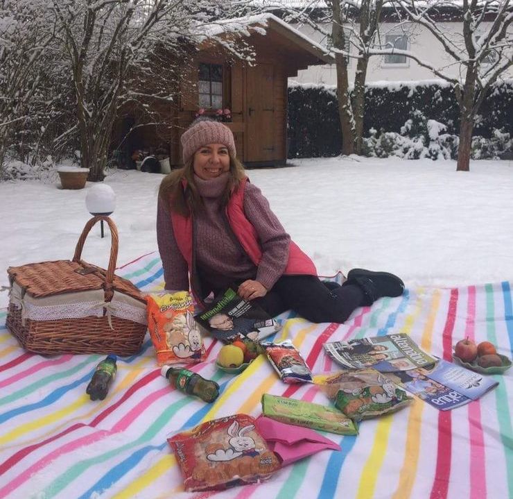 Carminha Barreto Reckentwald sentada em toalha com produtos sobralenses na neve de Munique